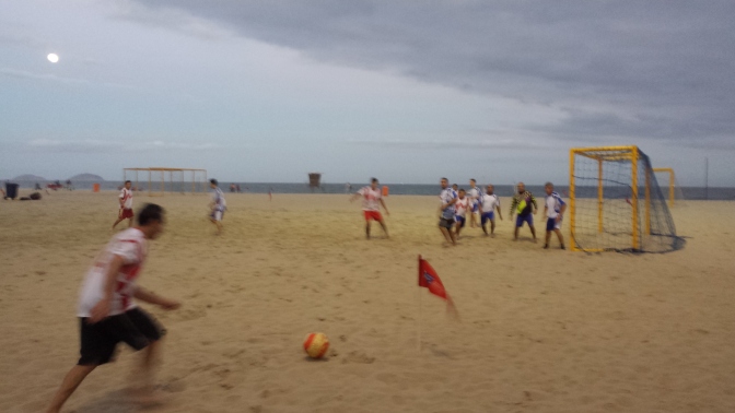 Early evening on the beach, the floodlights come on and the footballs come out